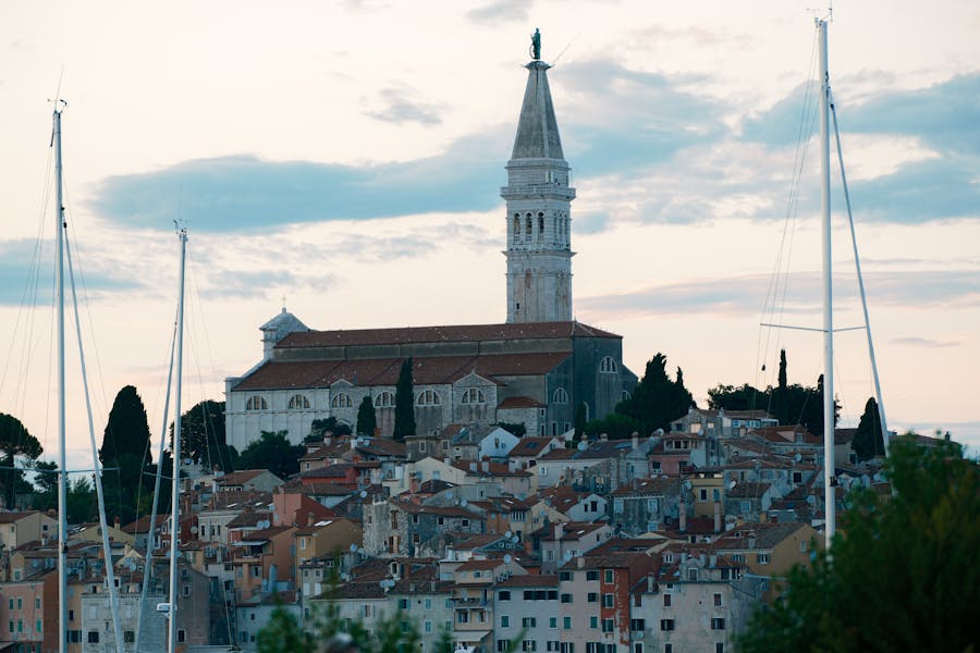 Coastal town with sailboats, historic church, Mediterranean architecture, and ocean view.