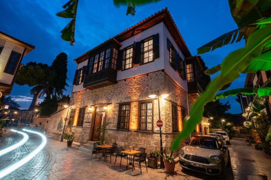 Historic Mediterranean stone hotel at blue hour with outdoor café, cobblestone street, and light trail.