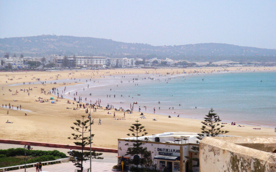 Sunny Mediterranean beach with turquoise sea, crowded shoreline, beachfront hotels and CHALET DE LA PLAGE restaurant.