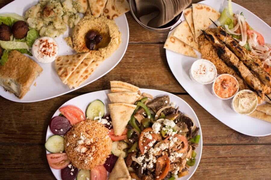 Middle Eastern cuisine spread: falafel, hummus, rice, grilled skewers, fresh vegetables, pita bread.