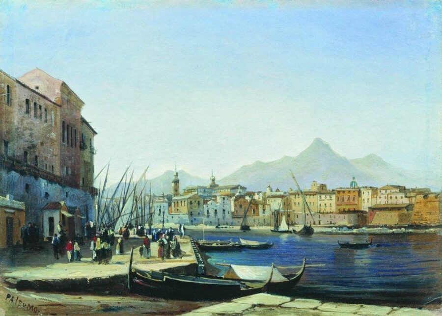 Bustling Mediterranean harbor with boats, historic architecture, and picturesque mountain backdrop.