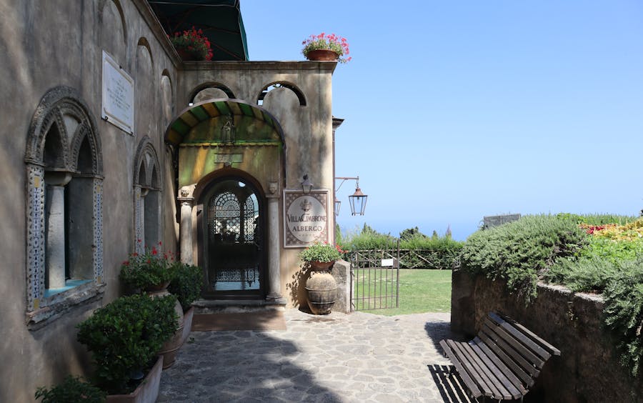 Mediterranean villa entrance with rustic architecture and lush greenery.