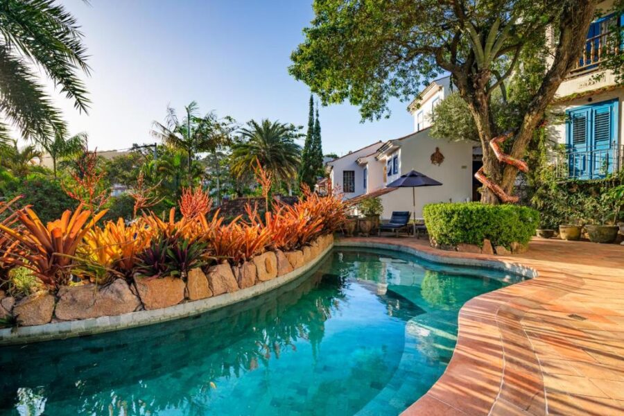 Mediterranean villa boutique hotel pool with lush garden, palm trees and relaxing sun loungers.