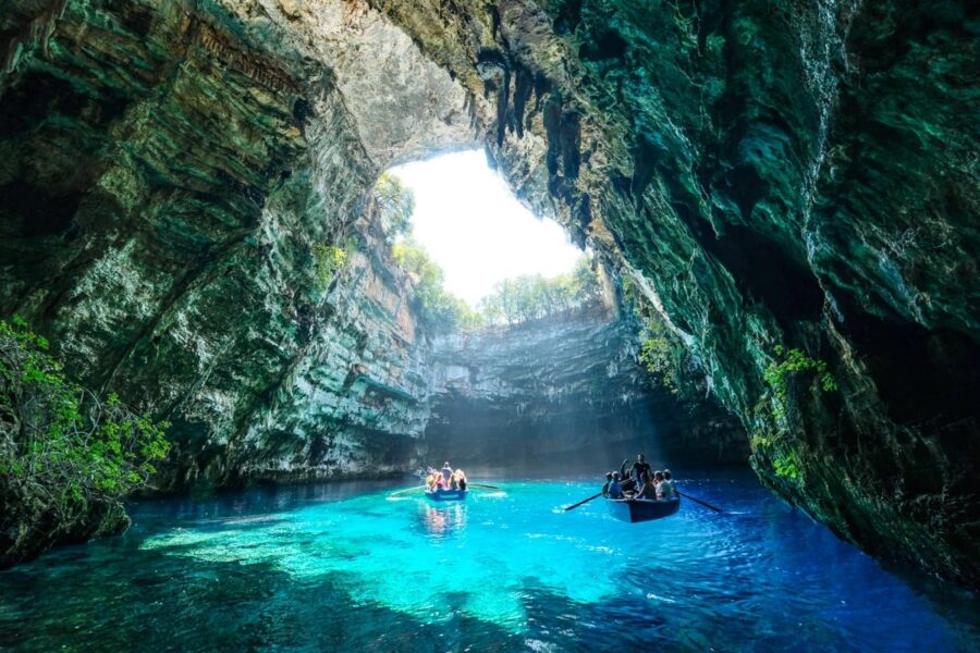 Breathtaking Melissani Cave: vibrant waters, majestic rock formations, sunlit depths, and exploring visitors.