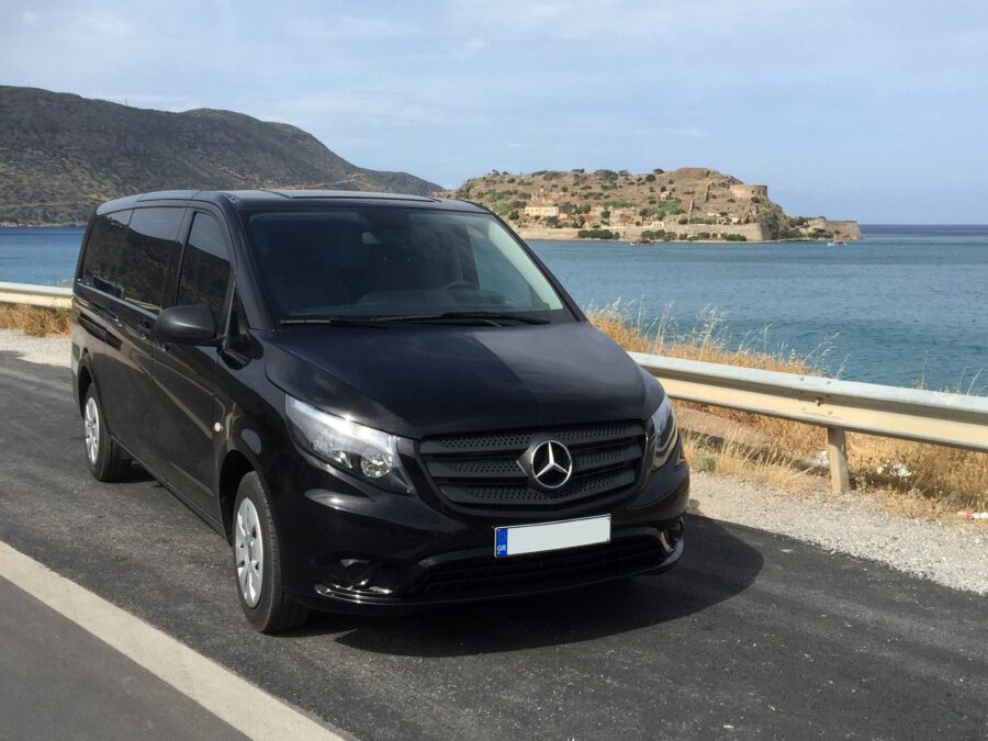 Heraklion taxi Mercedes black van parked on coastal road.
