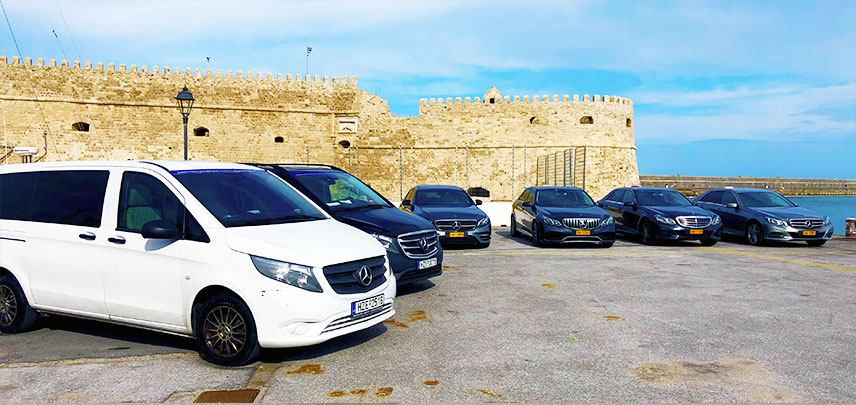 Mercedes taxi fleet parked by a coastal fortress in Crete.