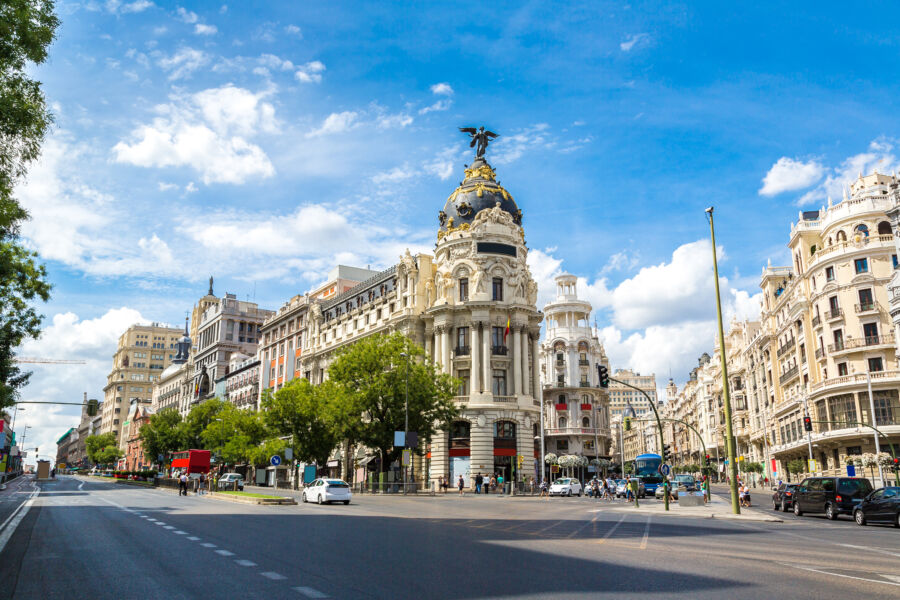 The iconic Metropolis Building in Madrid, Spain, with a vibrant street scene highlighting urban life and architecture