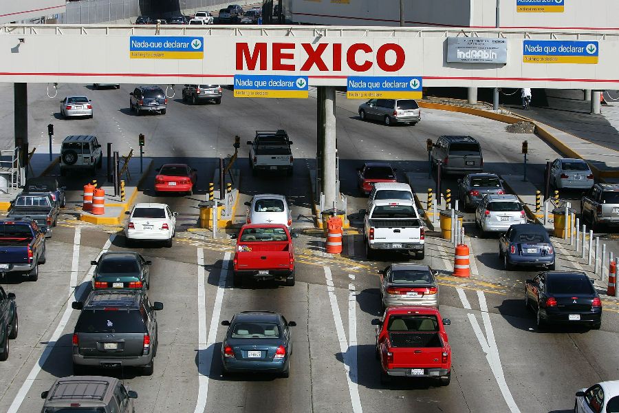 Busy Mexico border crossing with vehicles, traffic signs, and Nada que declarar notices.