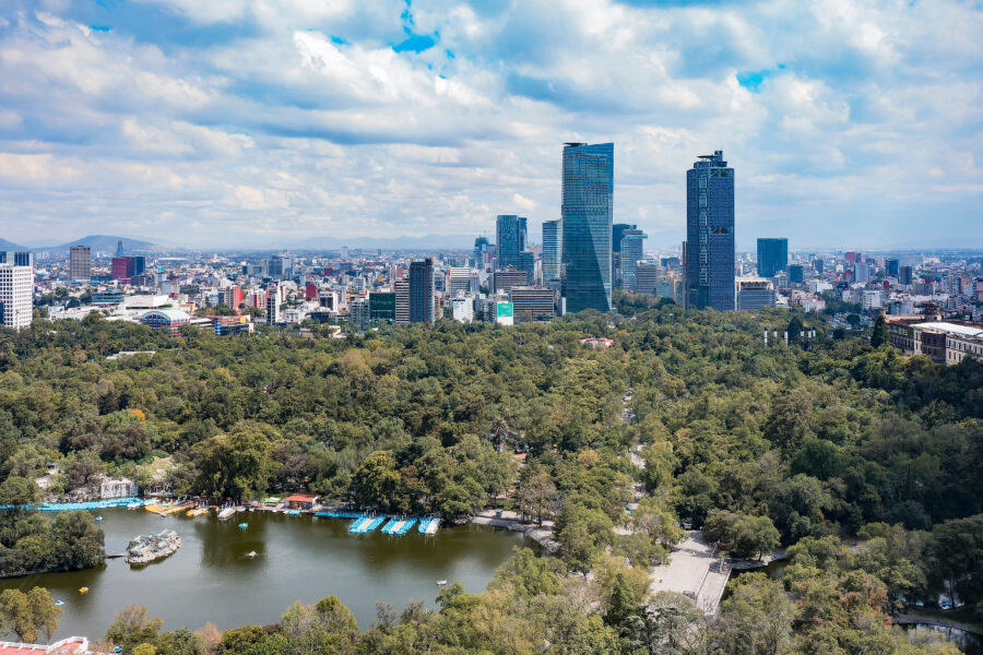 Aerial view of Chapultepec Park with Mexico City's skyline in the background, showcasing green space amidst urban landscape
