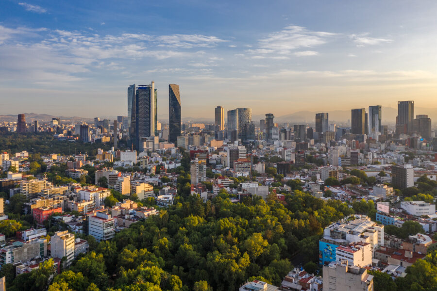 Aerial view of Mexico City's skyline at sunrise, featuring Paseo de la Reforma and Parque España bathed in warm light