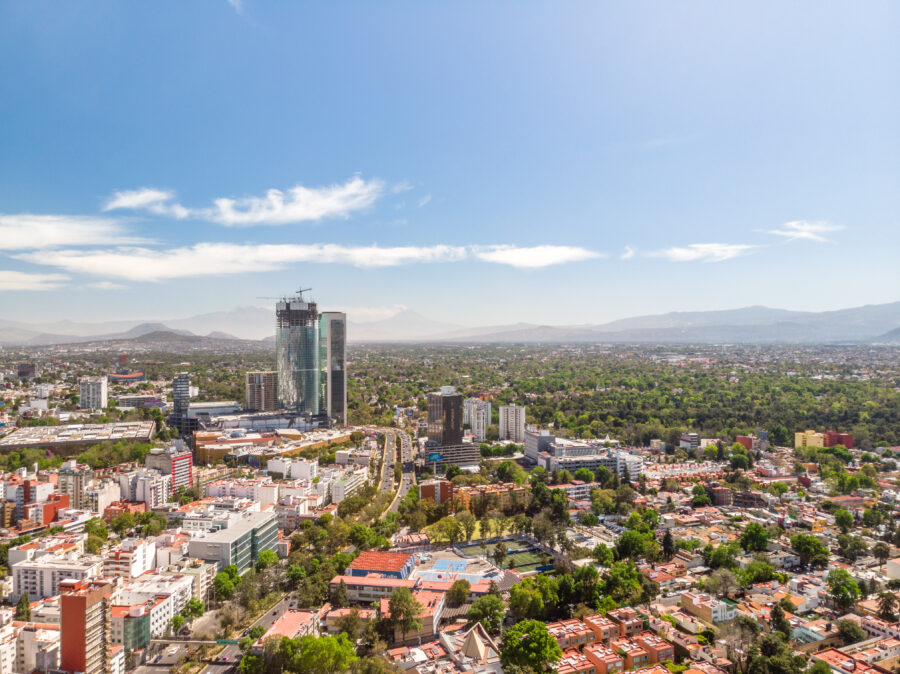 Panoramic aerial shot of the tallest building in Mexico City under construction, with a bright blue sky in the background