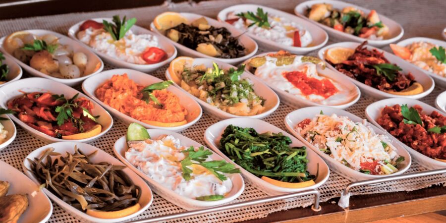 Colorful Mediterranean meze and tapas dips in small white bowls on a buffet platter.