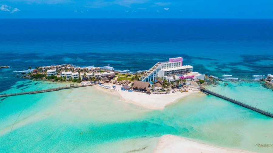 Aerial view of Isla Mujeres, Mexico, showcasing a tropical island with a dock extending into the turquoise waters.
