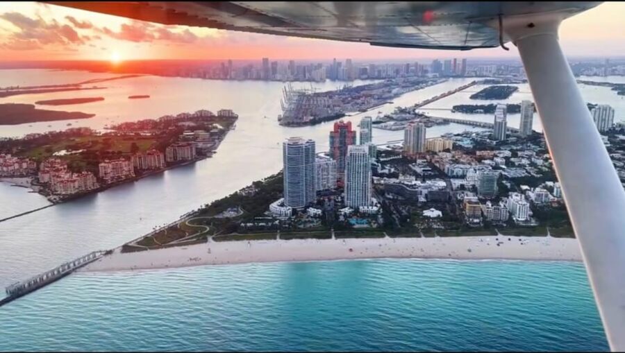 Aerial view of Miami sunset featuring cityscape, beach, islands, and ocean.