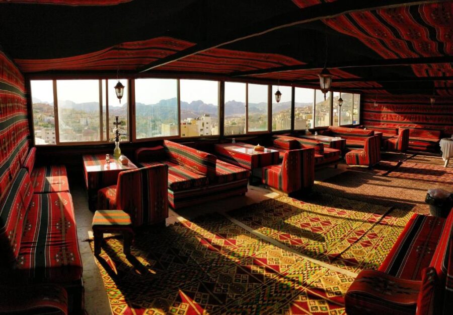 Traditional Middle Eastern lounge with patterned seating, hookah, and panoramic mountain view in Petra.