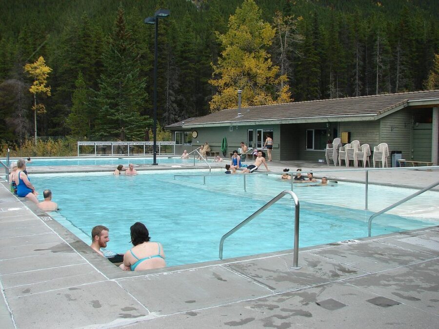 Visitors relax in a spacious pool at Miette Hot Springs, surrounded by scenic views in Canada.
