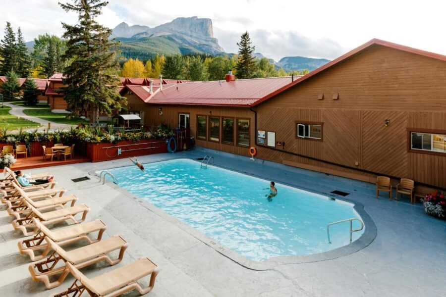 Miette Mountain Cabins features a pool and chairs, set against a stunning mountain backdrop in Jasper, Canada.
