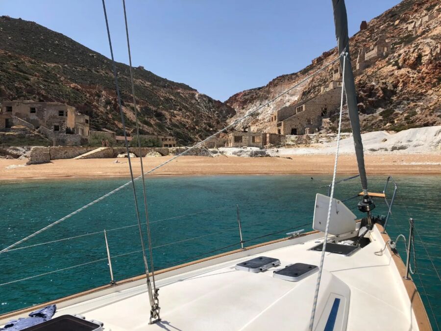 Sailboat docked in calm waters near a cliff, showcasing the scenic view from the Milos and Poliegos Boat Tour.
