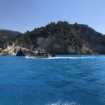 Boat is anchored in the clear blue waters beside a cliff on Milos Island, highlighting the scenic coastal landscape.