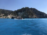 Boat is anchored in the clear blue waters beside a cliff on Milos Island, highlighting the scenic coastal landscape.