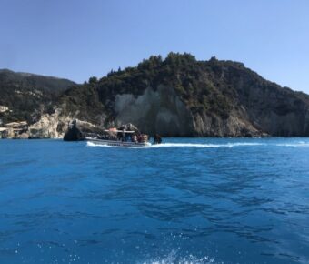 Boat is anchored in the clear blue waters beside a cliff on Milos Island, highlighting the scenic coastal landscape.
