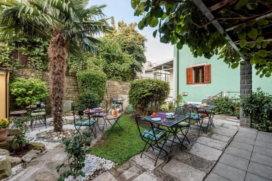 Outdoor seating area with tables and chairs in front of a green house at Miracolo di Mare Trend, Piran, Slovenia.