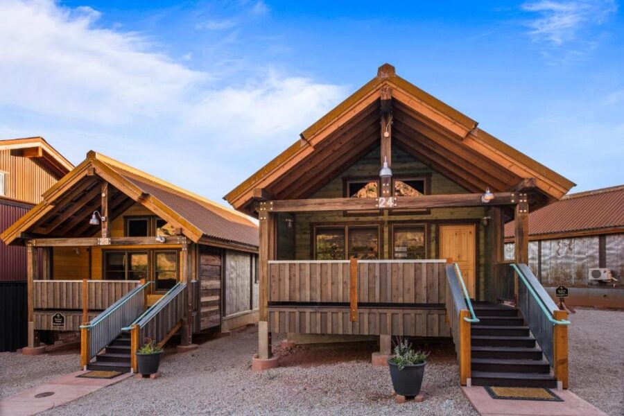 Two small cabins with wooden floors and stairs at Moab Springs Ranch, surrounded by natural scenery.
