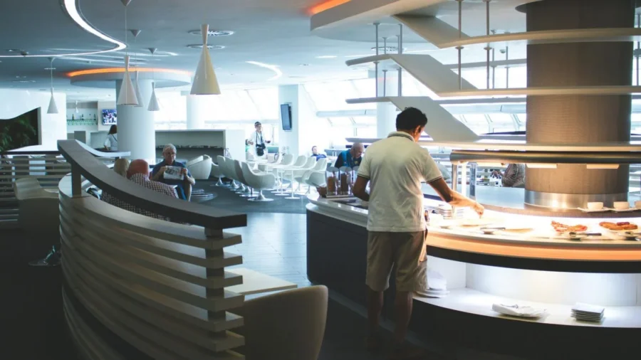 Modern airport lounge with buffet, sleek design, natural light, and relaxed atmosphere.