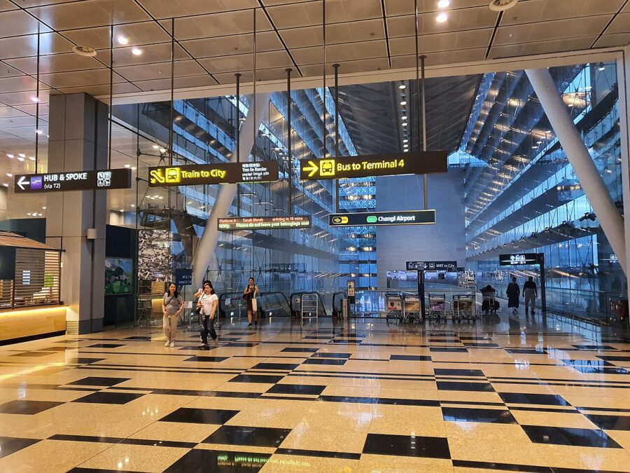 Modern Changi Airport terminal interior with signs for city train and Terminal 4 bus.