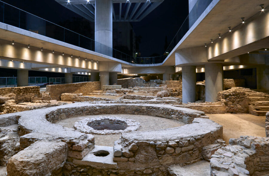 Ancient ruins beneath modern architecture at Acropolis Museum site, dramatic lighting enhances textures.