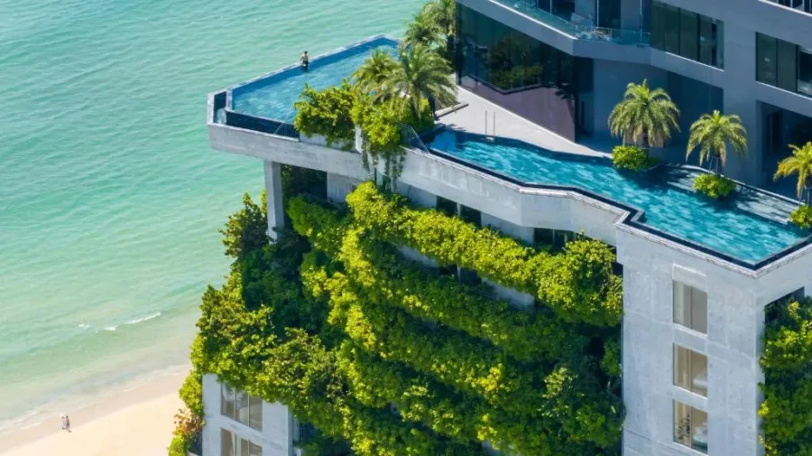 Luxury beachfront infinity pool tower with rooftop palm trees, vertical gardens, and panoramic ocean views.
