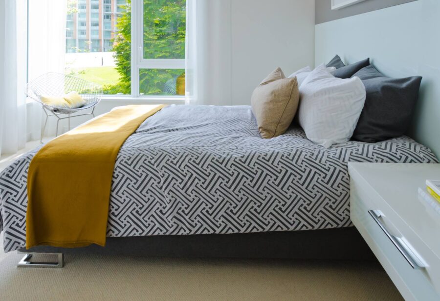 Modern minimalist bedroom with natural light, geometric bedding, and serene decor.