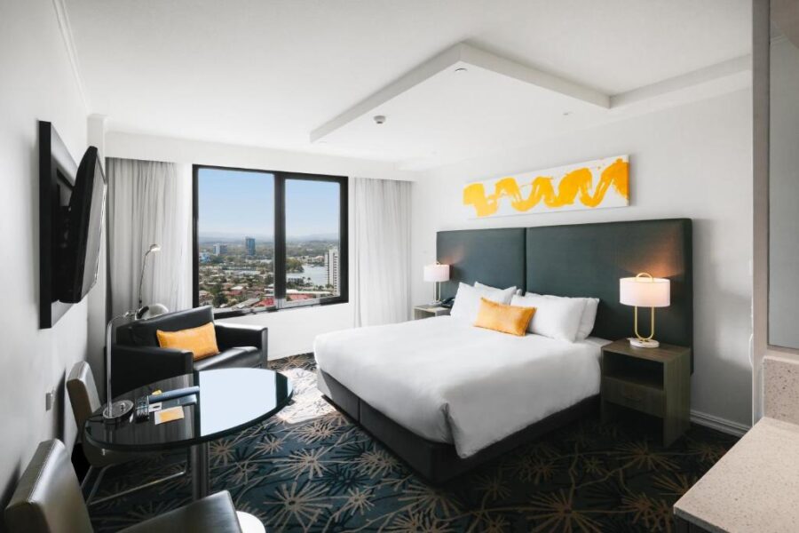 Modern Gold Coast hotel room with king bed, city skyline view, contemporary decor, and workspace.
