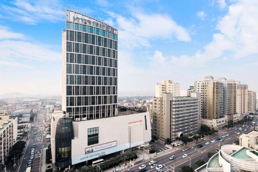 Modern Lotte City Hotel high‑rise tower on busy urban street with surrounding apartment buildings.