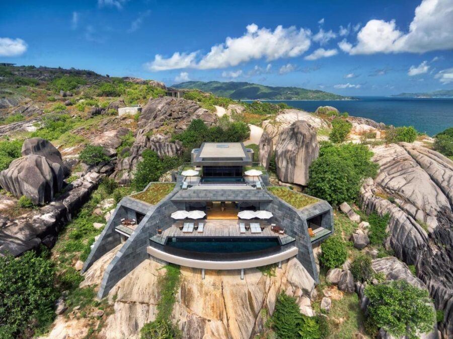 Luxury cliffside villa with infinity pool overlooking turquoise ocean and dramatic rocky coastline.