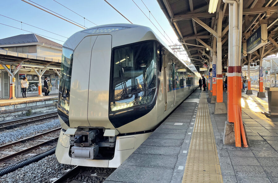 Modern Japanese commuter train at Tobu Railway station platform under overhead wires in sunlight.