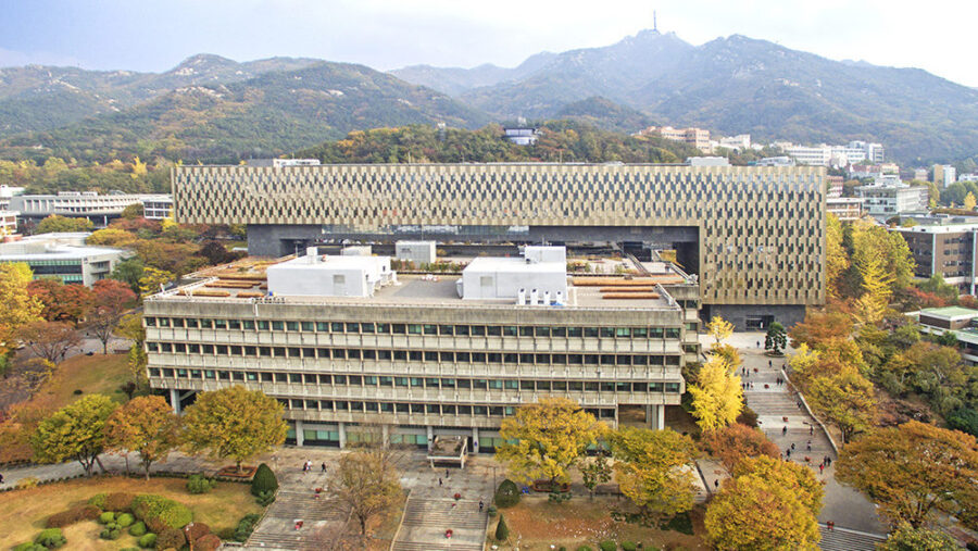 Modern campus with innovative architecture, traditional buildings, autumn foliage, and mountain backdrop.