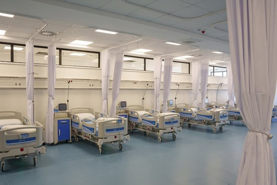 Modern hospital room with adjustable beds, monitors, and privacy curtains in clean, organized environment.