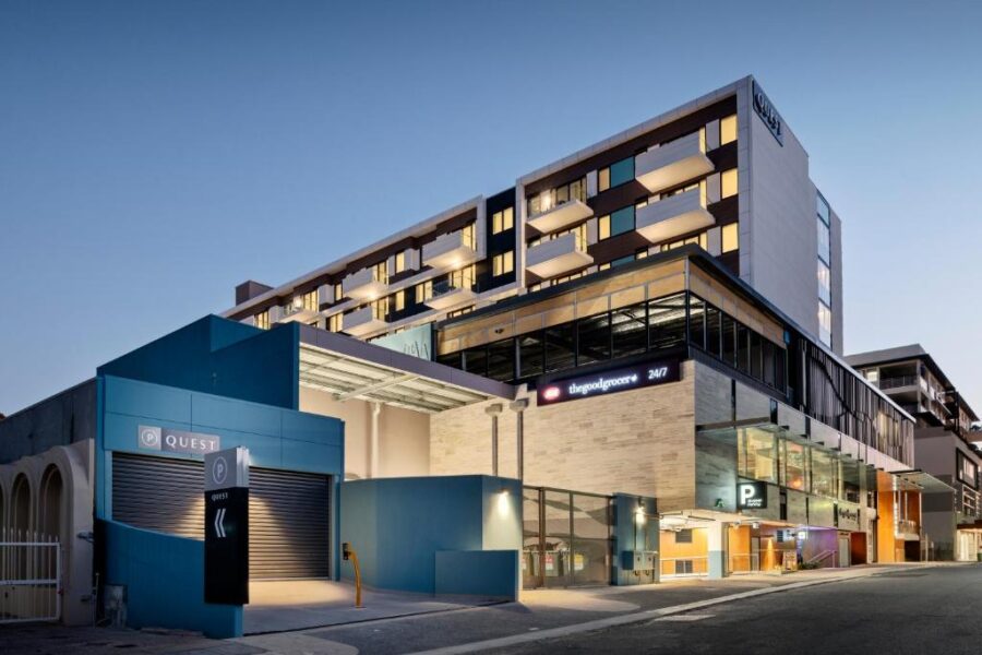 Modern South Perth mixed‑use building with Quest hotel, Good Grocer supermarket and parking at dusk.