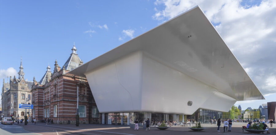 Modern art museum plaza with futuristic white extension and historic brick building in Amsterdam.