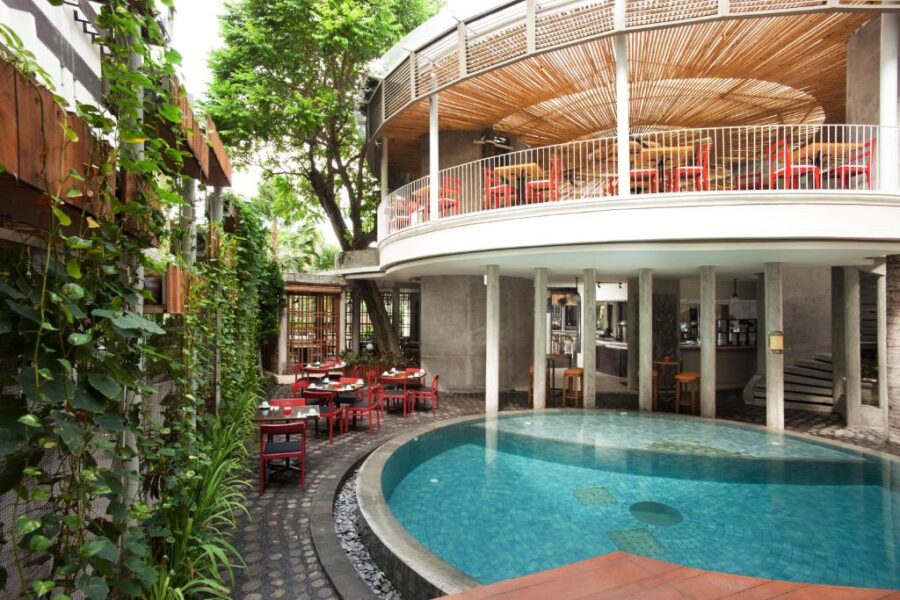 Modern open-air poolside restaurant and bar at Grandmas Plus Hotel Seminyak with tropical decor.