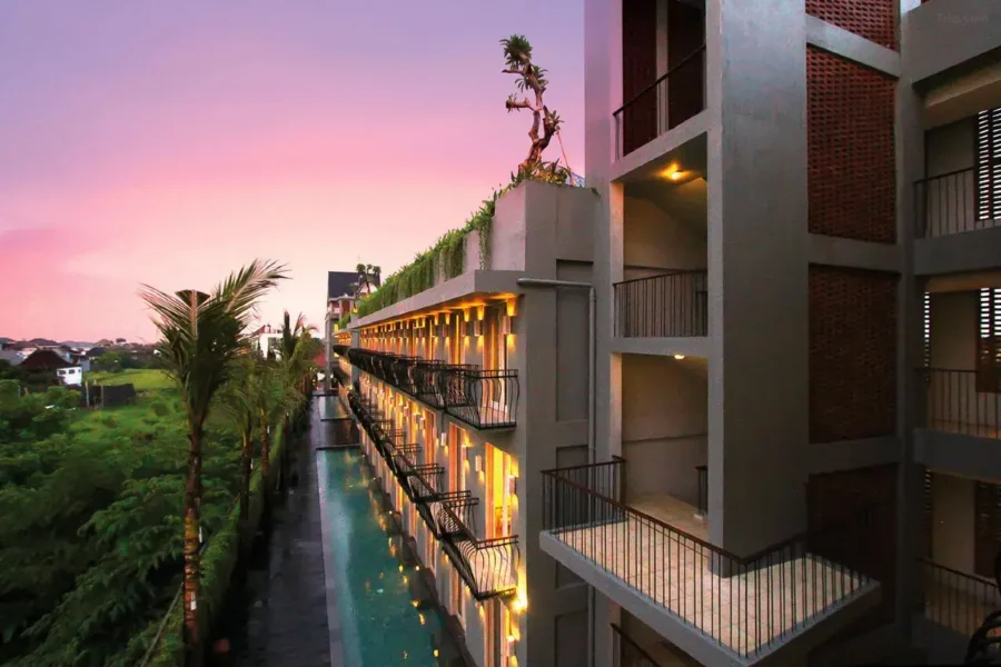 Modern Bali resort with illuminated pool, palm trees, and sunset sky at Frii Echo Beach.