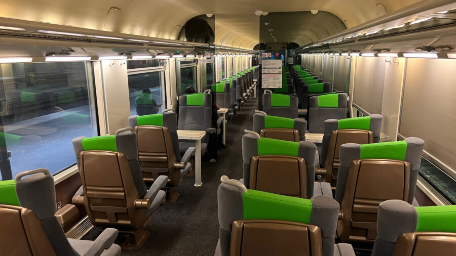 Modern train compartment with gray and green seats, spacious design, and ergonomic seating.
