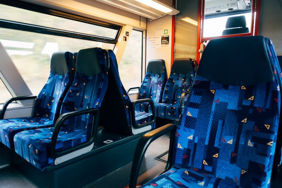 Modern train interior with colorful seats, large windows, vibrant design, and sleek metallic finishes.