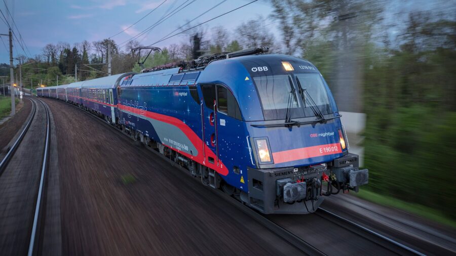 Modern OBB Nightjet train in motion, vibrant design, nighttime travel through scenic landscape.