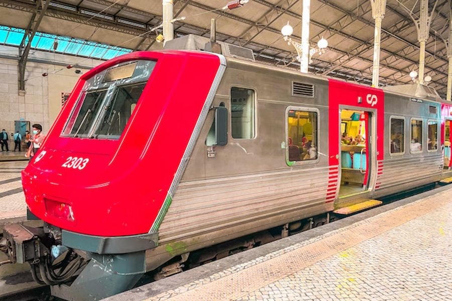 Modern red train at a lively station with passengers, Lisbon to Sintra route.