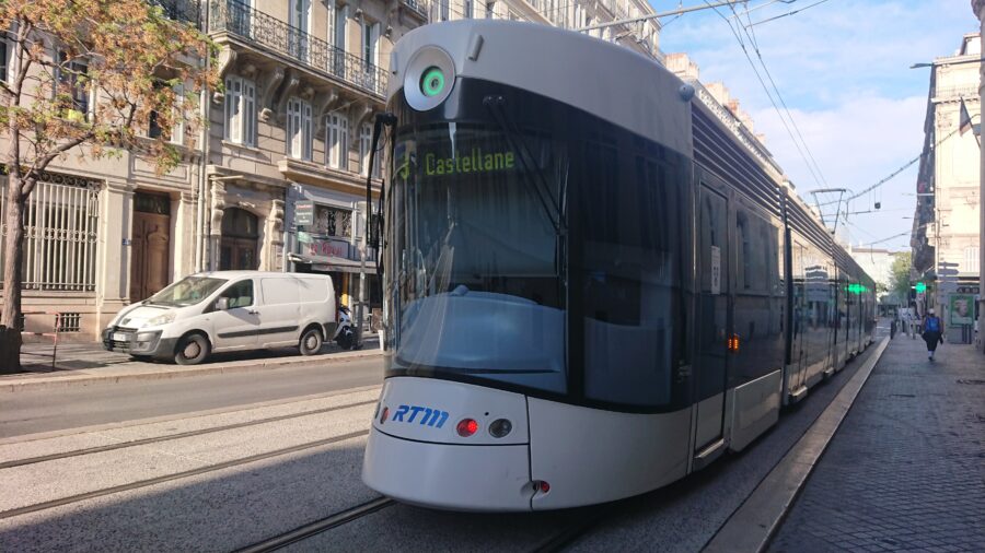 Modern tram on historic cobblestone street in Marseille, France, showcasing urban transportation.