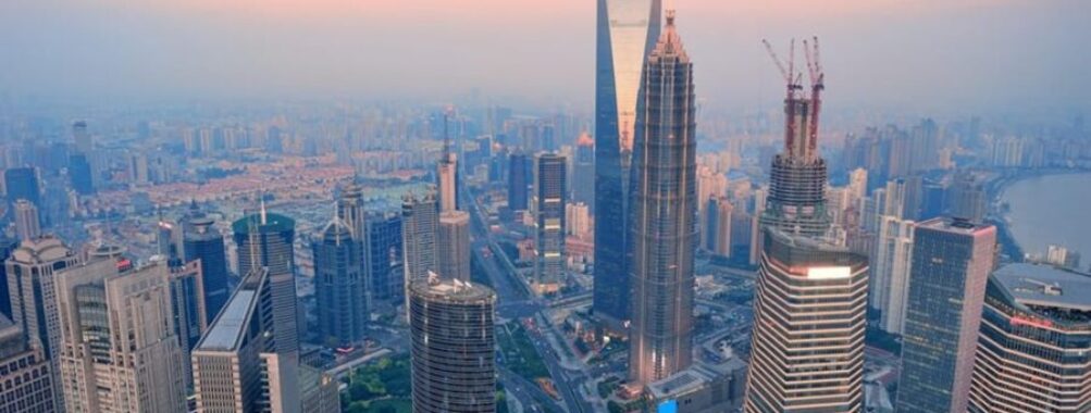 Aerial view of Shanghai modern urban skyline with diverse skyscrapers and vibrant cityscape at dusk.