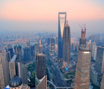 Aerial view of Shanghai modern urban skyline with diverse skyscrapers and vibrant cityscape at dusk.