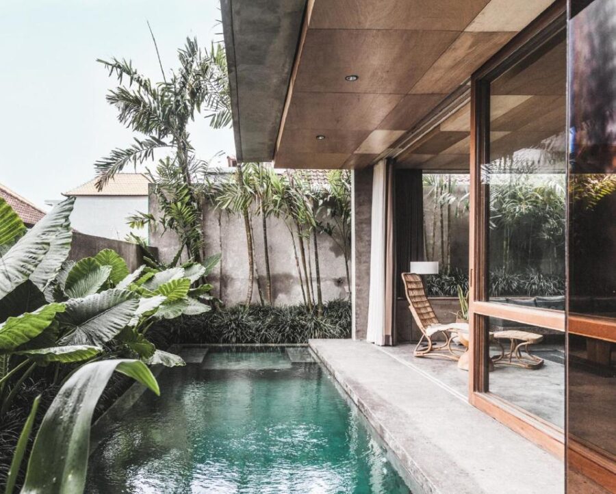 Modern villa poolside courtyard with private turquoise lap pool, tropical plants, and outdoor lounge.